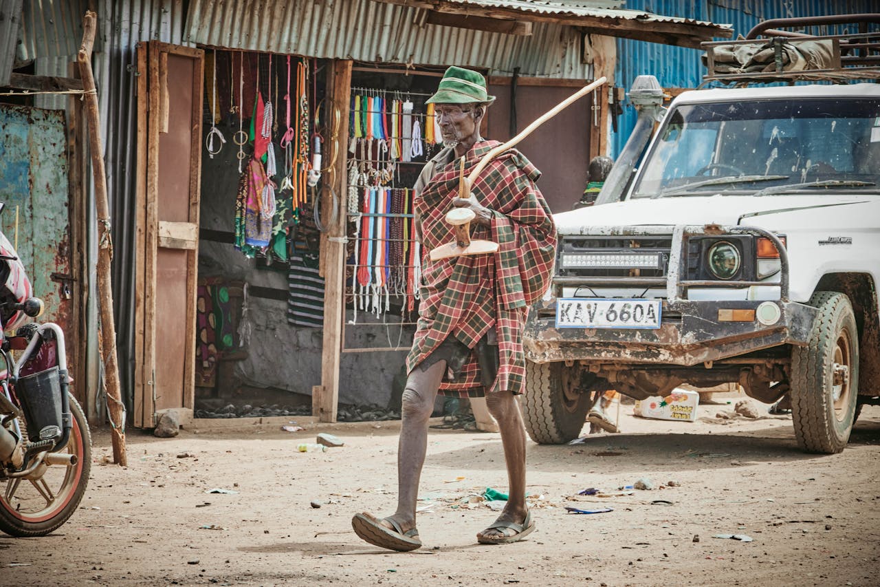 A traditional Kenyan scene featuring a local musician playing an instrument on a street in Kenya, with vibrant market goods.
